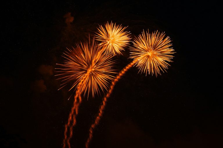 Three golden fireworks explode in the night sky.