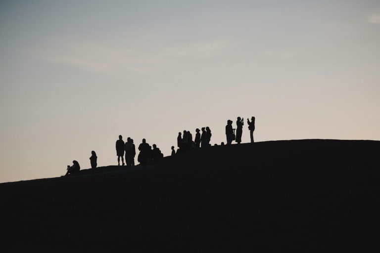 People silhouetted on a hilltop against a pale sky